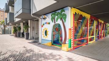 A children's play area with colorful murals and a netted climbing structure.