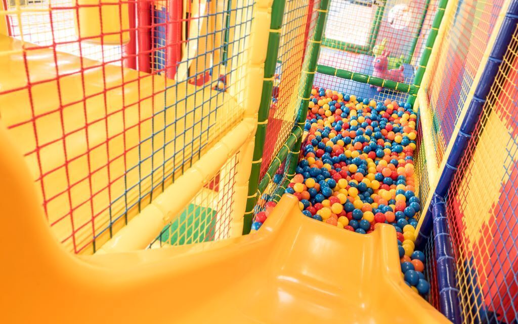 A play area with a yellow slide and a ball pit filled with multicolored balls.