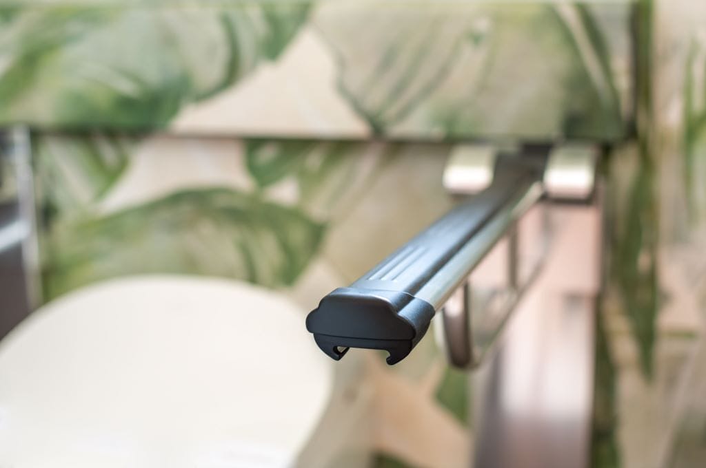 A close-up of a metal railing with a black end cap, likely part of a balcony or outdoor area.