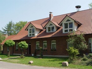 A two-story brick house with a red-tiled roof, dormer windows, and a chimney. - Ferienwohnung Zum Storchenblick (Walsrode)