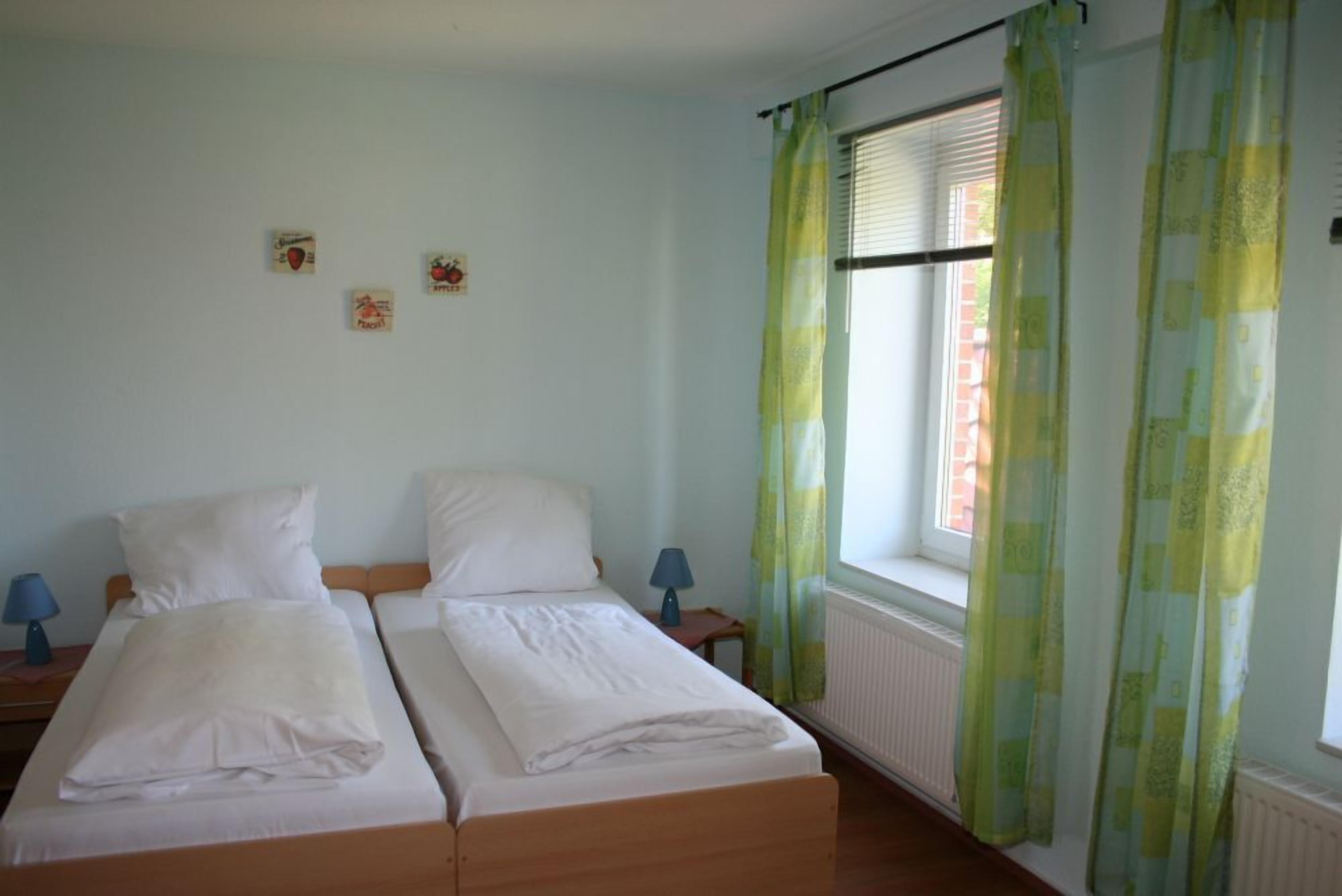 A twin room with two beds, a window with blinds, and a radiator.