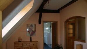 A hallway with a wooden cabinet, a painting, and a potted plant. - Ferienwohnung Zum Storchenblick (Walsrode)