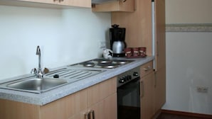 Une cuisine de taille réduite, dotée d’armoires en bois, d’un plan de travail en granit, d’une cuisinière et d’un évier.