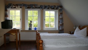 Une chambre avec deux lits, un bureau et une fenêtre avec des rideaux.