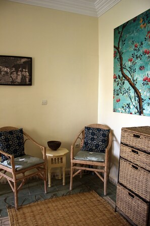 A room with two wicker chairs, a small stool, and a woven mat on the floor. - Tifawin Home & Garden (Mirleft)