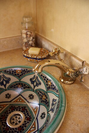 A bathroom sink with a decorative ceramic basin and a gold faucet. - Tifawin Home & Garden (Mirleft)