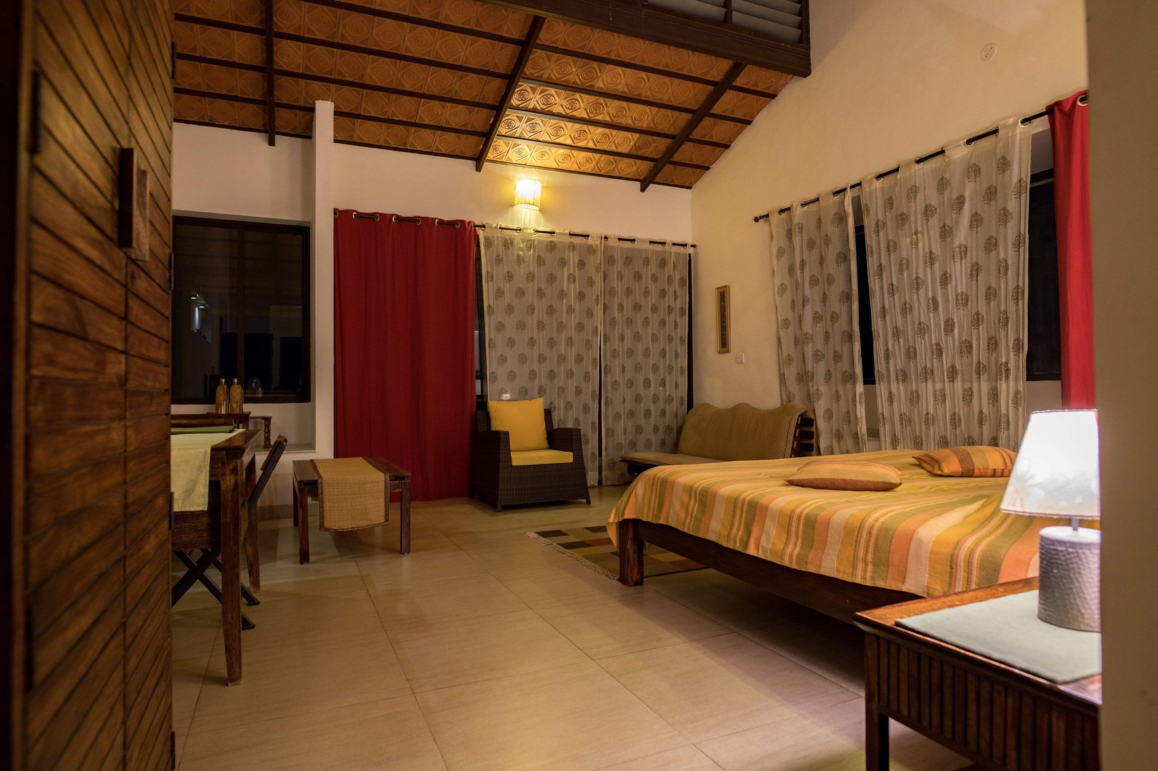 A bedroom with a bed, a chair, a desk, and a lamp.
