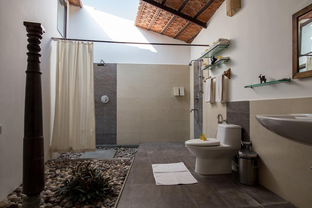 Une salle de bain moderne équipée d’une douche, de toilettes, d’un lavabo et d’étagères décoratives.