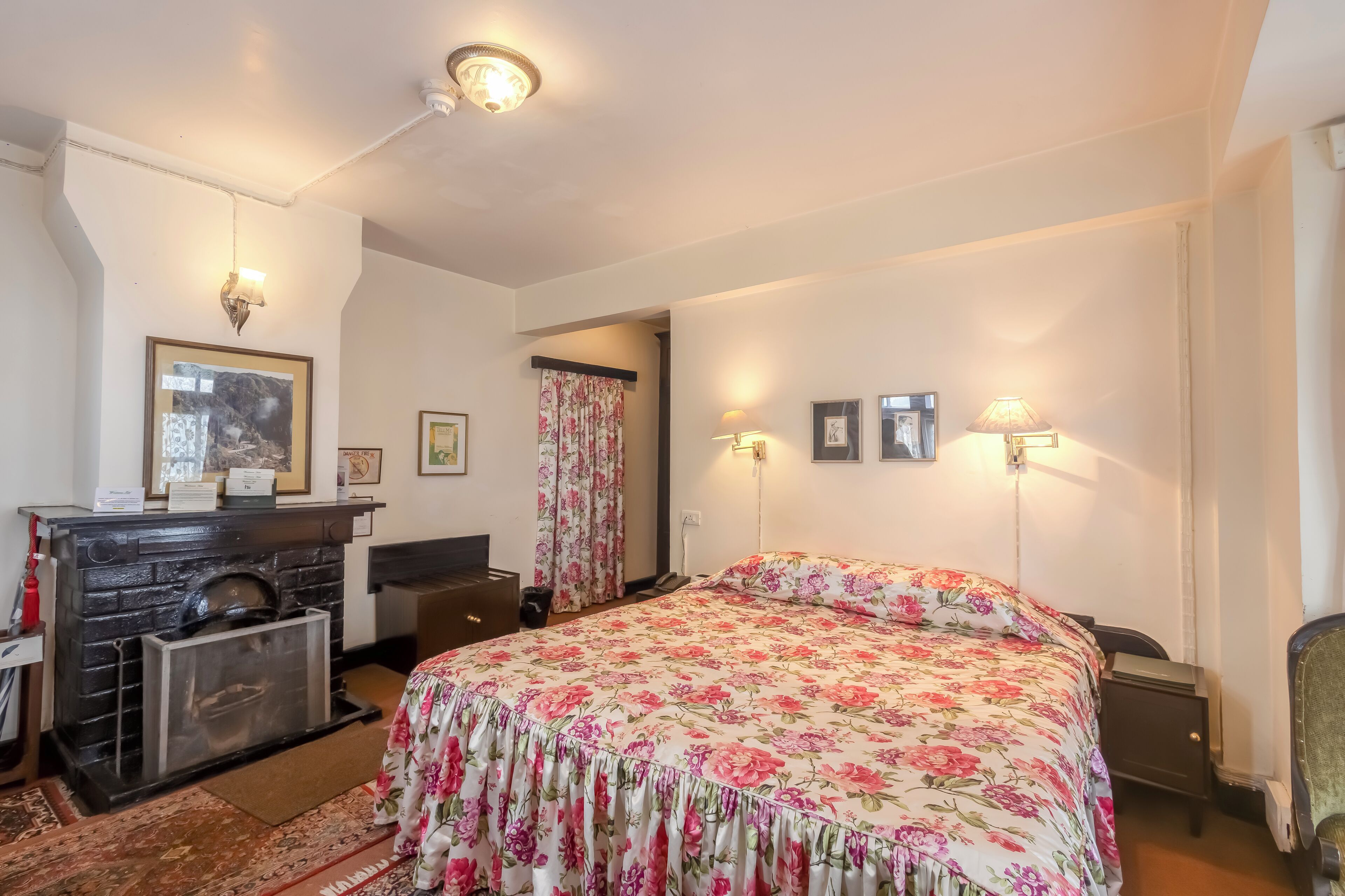 Un dormitorio con cama, tocador y chimenea.