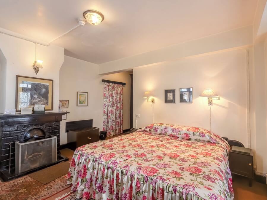Un dormitorio con cama, tocador y chimenea.