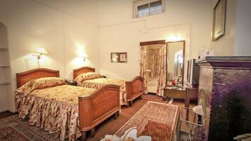 A bedroom with two wooden beds, a dresser, a mirror, and a small table with a vase.