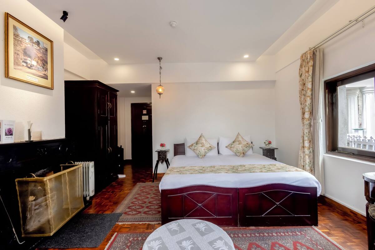 Une chambre à coucher avec un grand lit, un radiateur, une armoire en bois et un tableau encadré au mur.