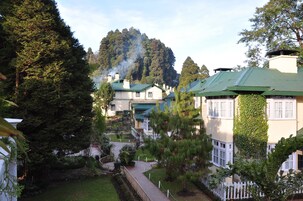 A hotel with multiple buildings, a pathway, and a forested hill in the background.