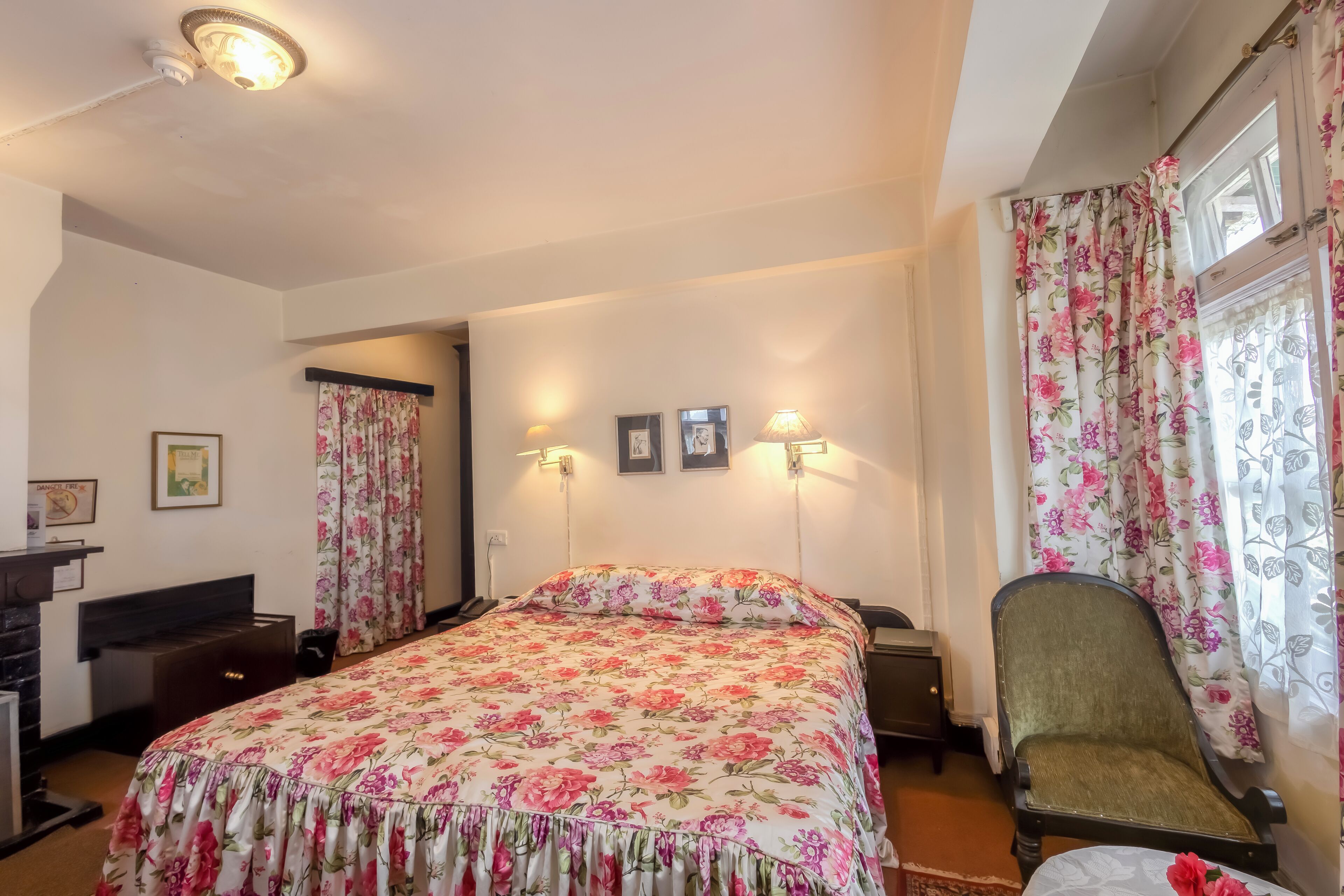 Un dormitorio con colcha estampada de flores, una silla, un escritorio y un aparador.