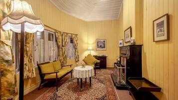 Una habitación con una pared amarilla, un tapete estampado, un sofá, una mesa con una lámpara y un televisor.