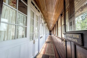 A corridor with wooden paneling, large windows with curtains, and a security door sign. - Windamere Hotel (Darjeeling)