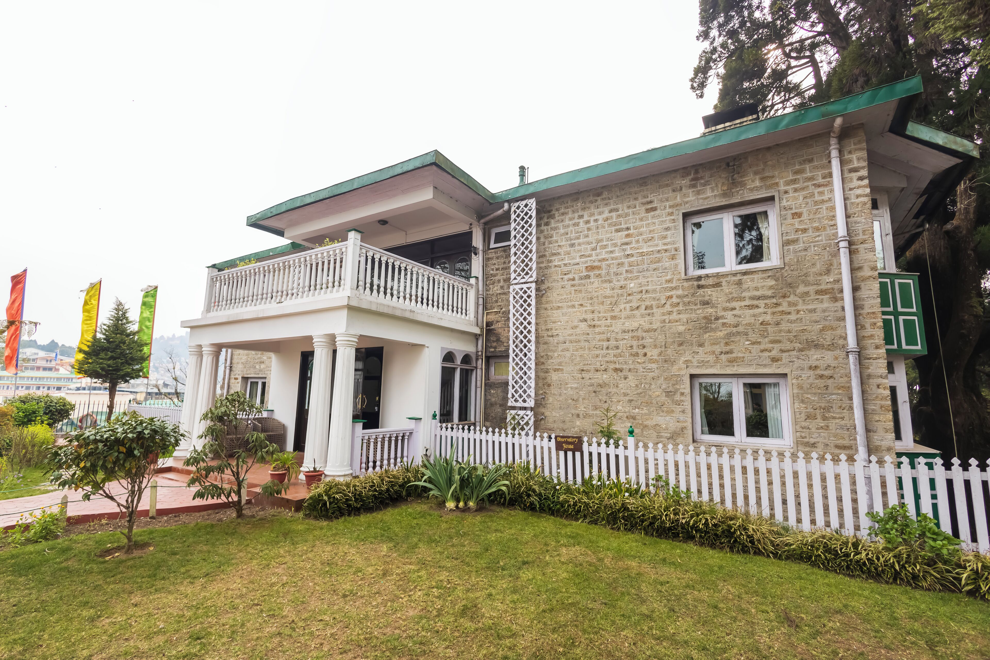 A two-story building with a balcony, white picket fence, and a sign indicating it is a hotel.