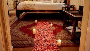 A bedroom with a bed, bedside tables, a nightstand, a lamp, a wooden chair, and a carpeted floor. - Windamere Hotel (Darjeeling)