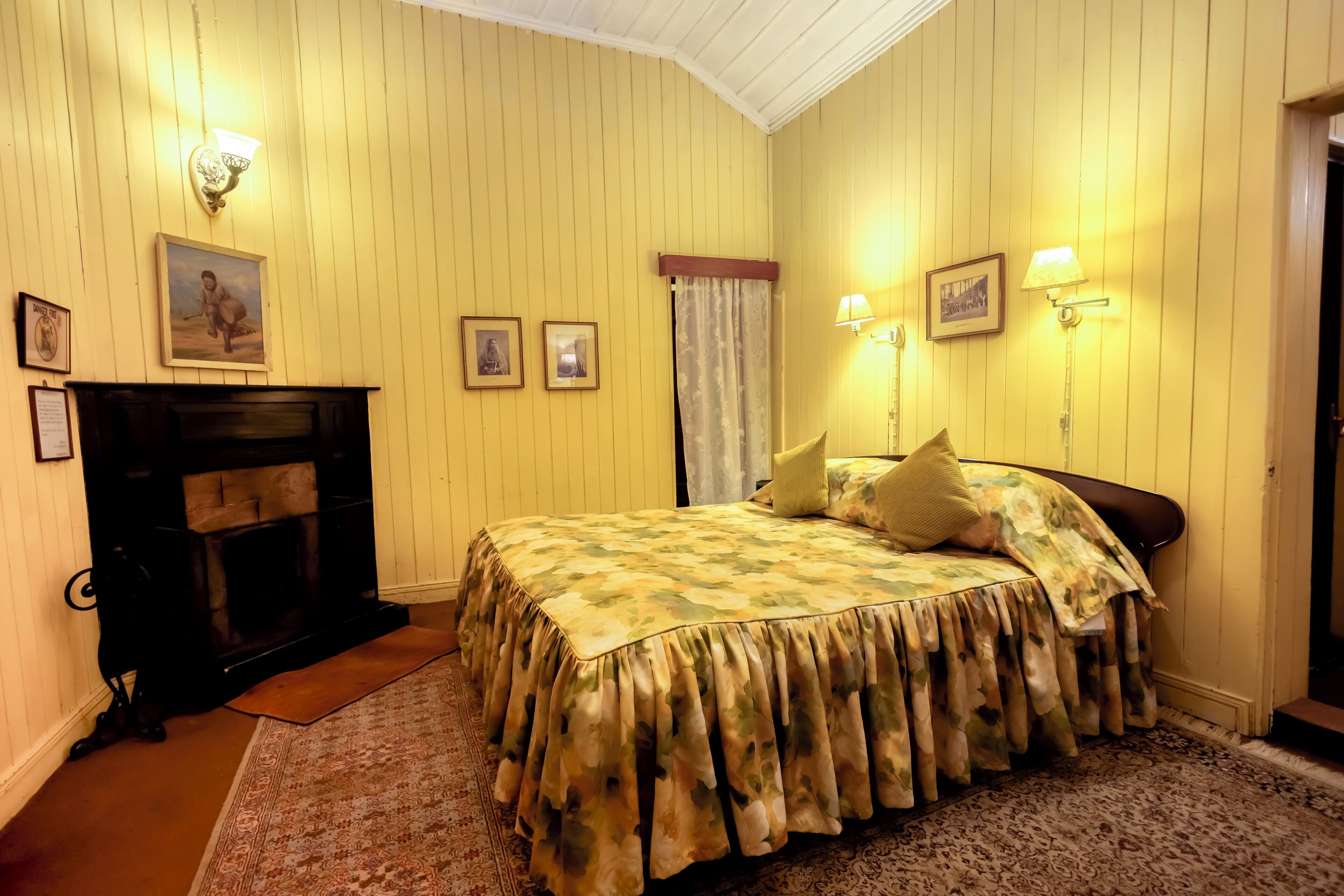 A room with a bed, a fireplace, and wall-mounted lamps.