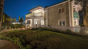 A two-story house with a balcony, a white picket fence, and a well-maintained lawn. - Windamere Hotel (Darjeeling)