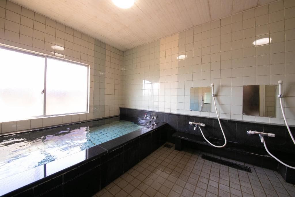 Baño público con una ventana grande, un lavabo y un espejo.