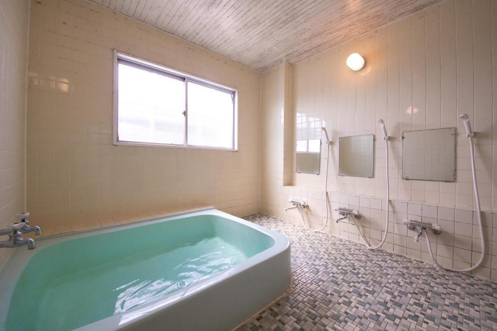 A bathroom with a bathtub, a window, and a shower area.