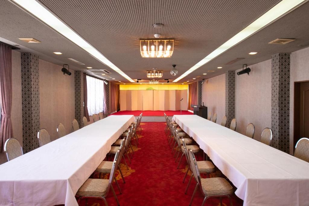 A conference room with a long table, chairs, a red carpet, and a chandelier.