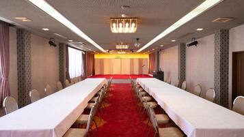A conference room with a long table, chairs, a red carpet, and a chandelier.