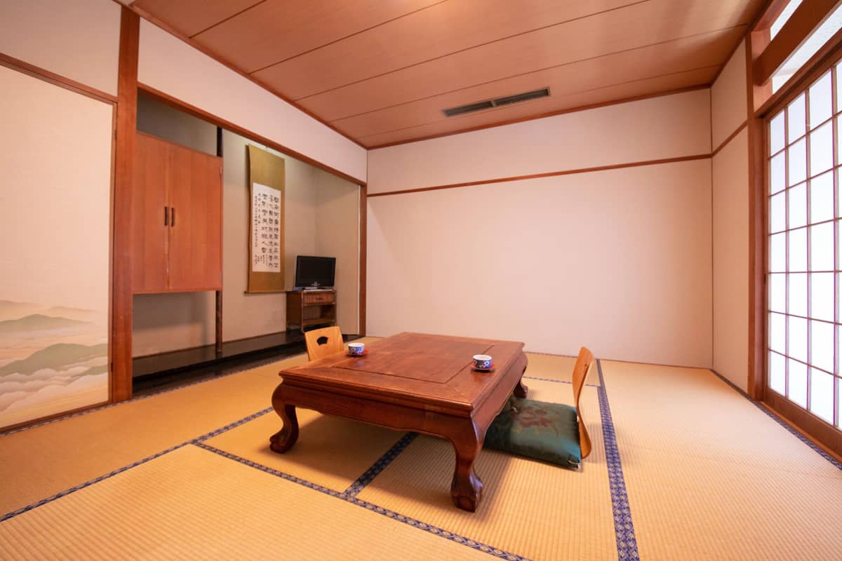 A traditional Japanese room with tatami flooring, a wooden table, and a sliding door.