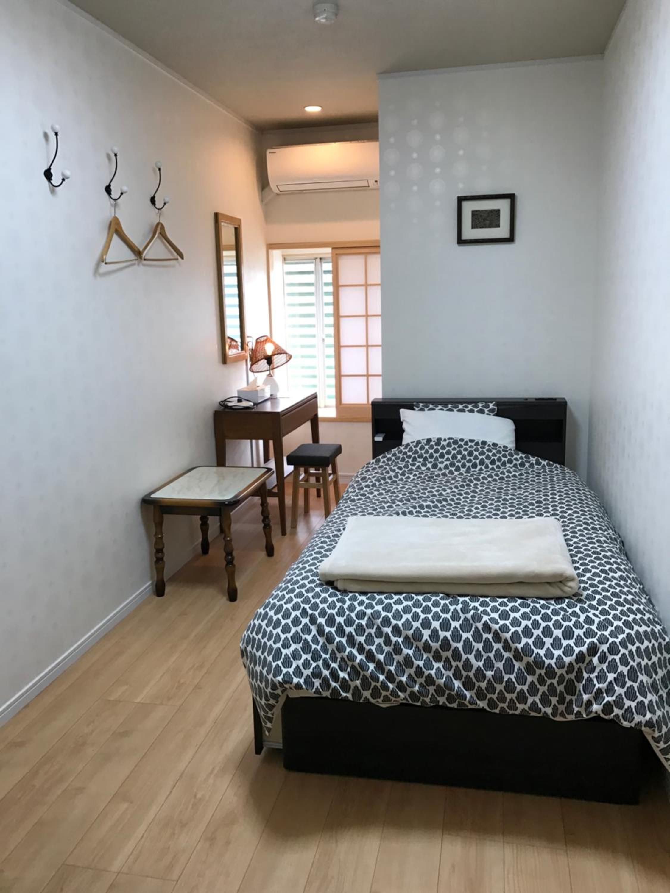 Une chambre à coucher avec un lit, un bureau, une chaise et une fenêtre.