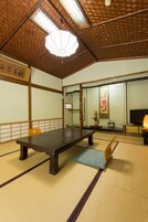 Una habitación japonesa tradicional con suelo de tatami, una mesa baja, un sofá y un televisor.