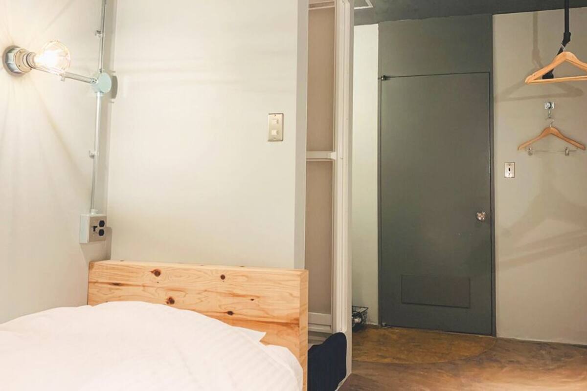 A bedroom with a bed, a bedside lamp, a wooden headboard, a closet, and a door.