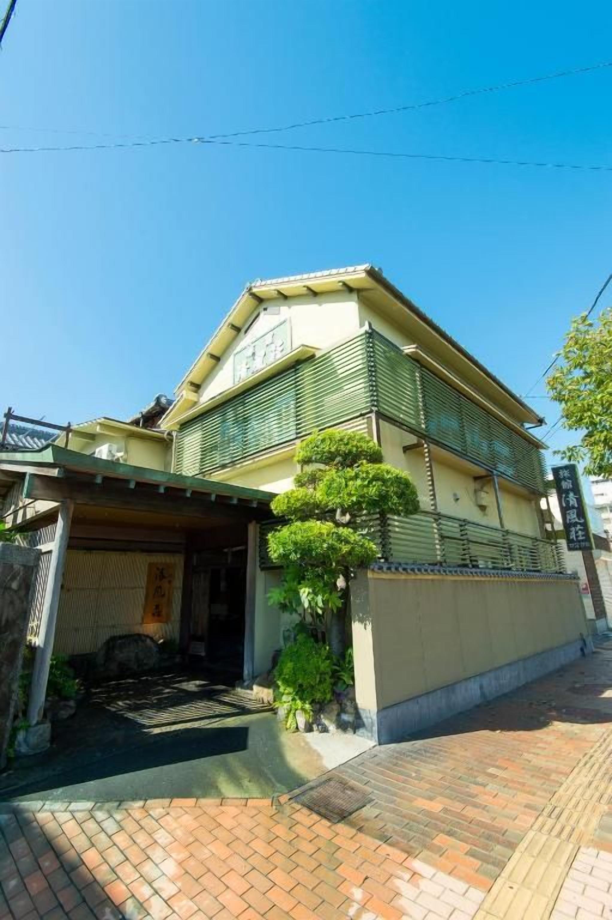 Ein traditionelles japanisches Haus mit überdachter Veranda, einem kleinen Garten und einem gefliesten Weg.