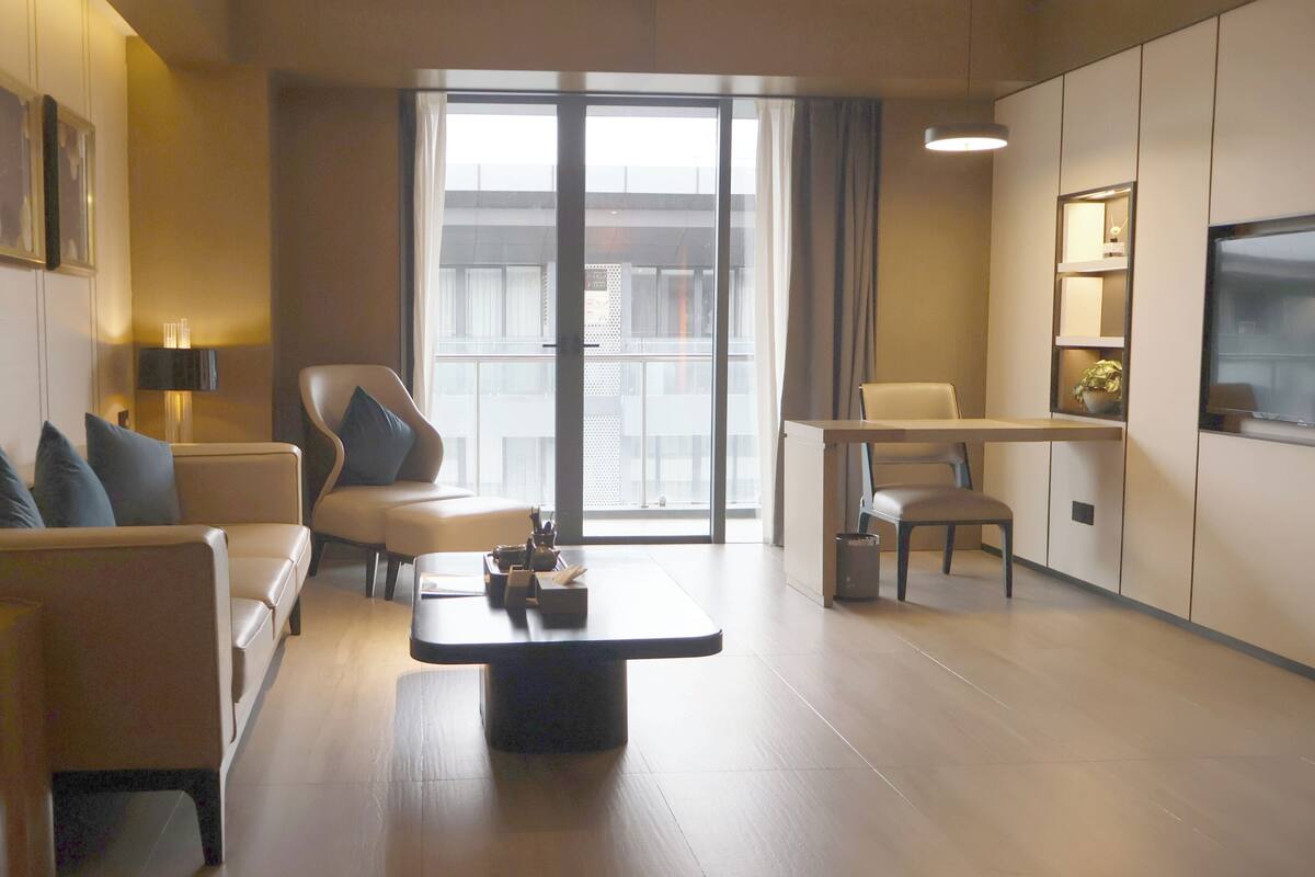 Ein modernes Wohnzimmer mit einer Couch, Sesseln, einem Couchtisch und einem Essbereich mit Tisch und Stühlen.