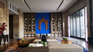 Een moderne lobby met een centraal zitgedeelte, boekenkasten en een groot decoratief kunstwerk.