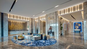 Een moderne lobby met een zithoek, een receptiebalie en een decoratieve wand met ingelijste foto's.