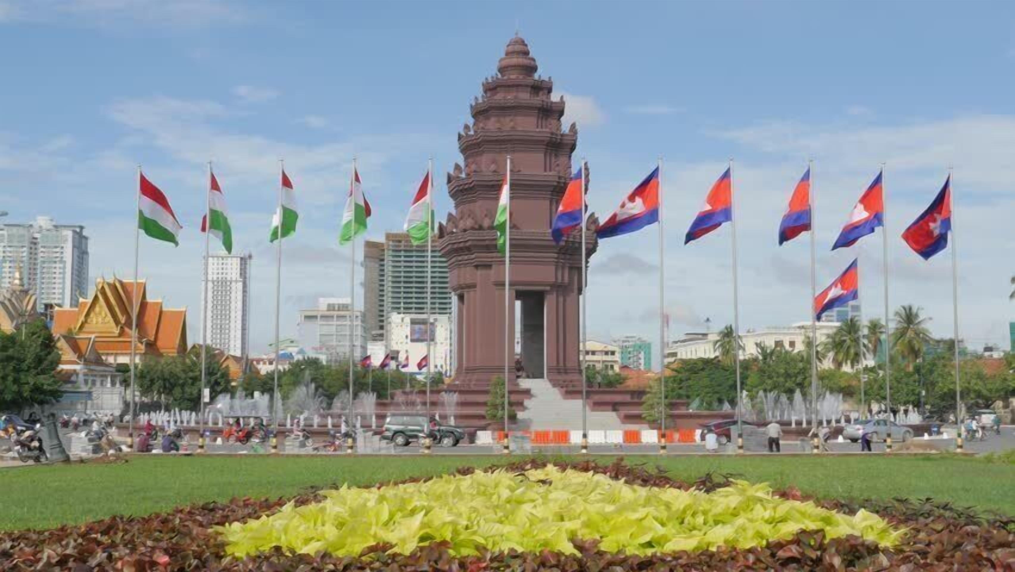A monument with multiple flags in a city square.
