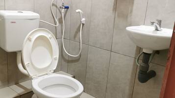 A bathroom with a toilet, a bidet, a sink, and a toilet paper holder on the wall.