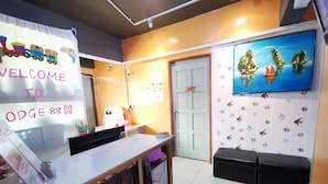 A reception area with a 'Welcome to ODG 88' sign, a reception desk, a seating area with a TV displaying a scenic island, and a door marked '01'. - Lodge88 2 (Ranau)