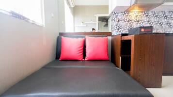 A seating area with a black cushioned bench and two red pillows.