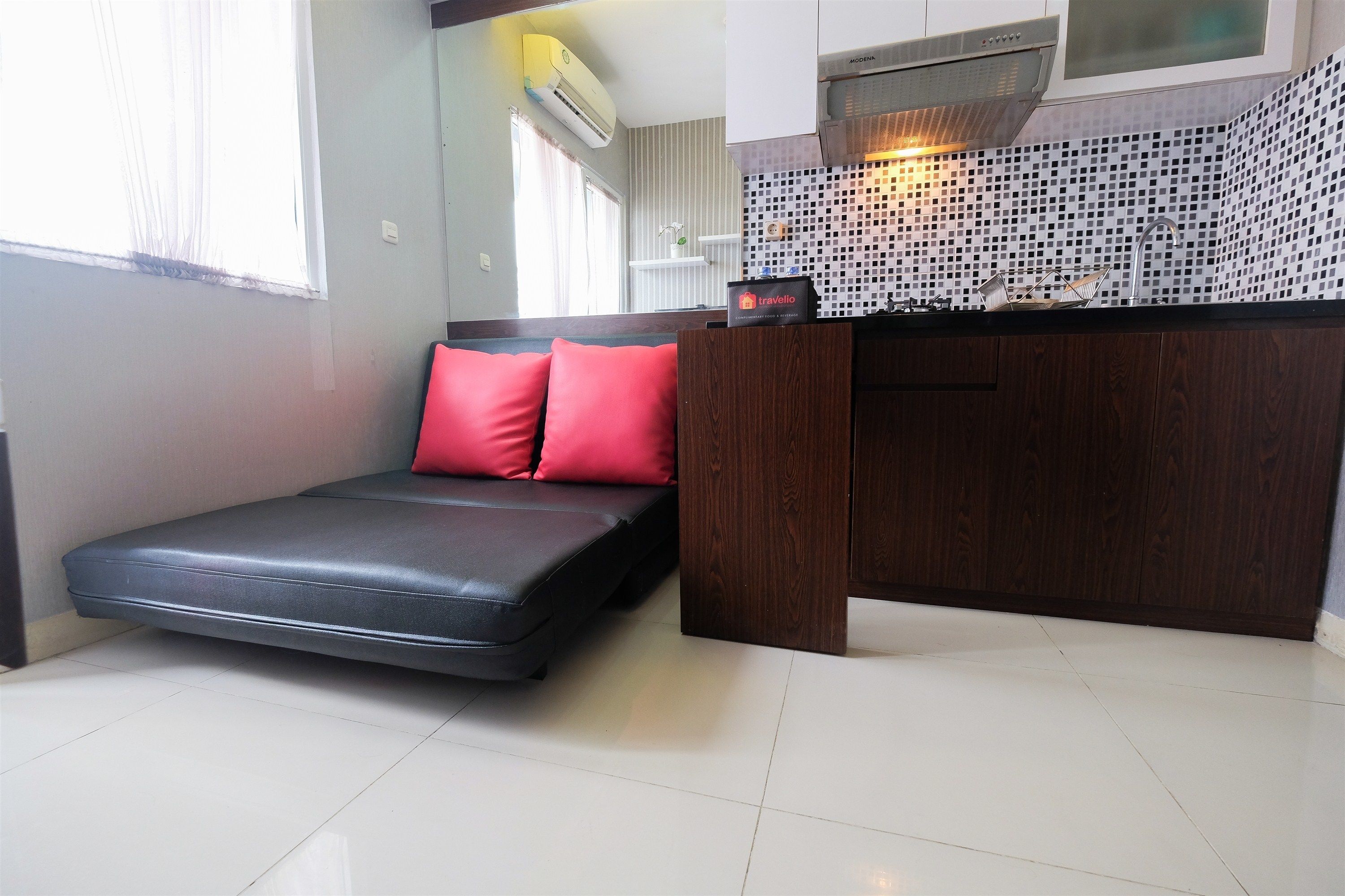 A compact room with a small bed, a kitchenette, and a window with curtains.