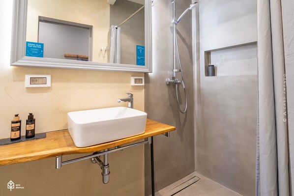 A modern bathroom with a rectangular sink, a handheld showerhead, and a mirror above the sink.