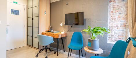 Une chambre moderne équipée d’un bureau, de deux chaises, d’une télévision et d’une plante en pot.