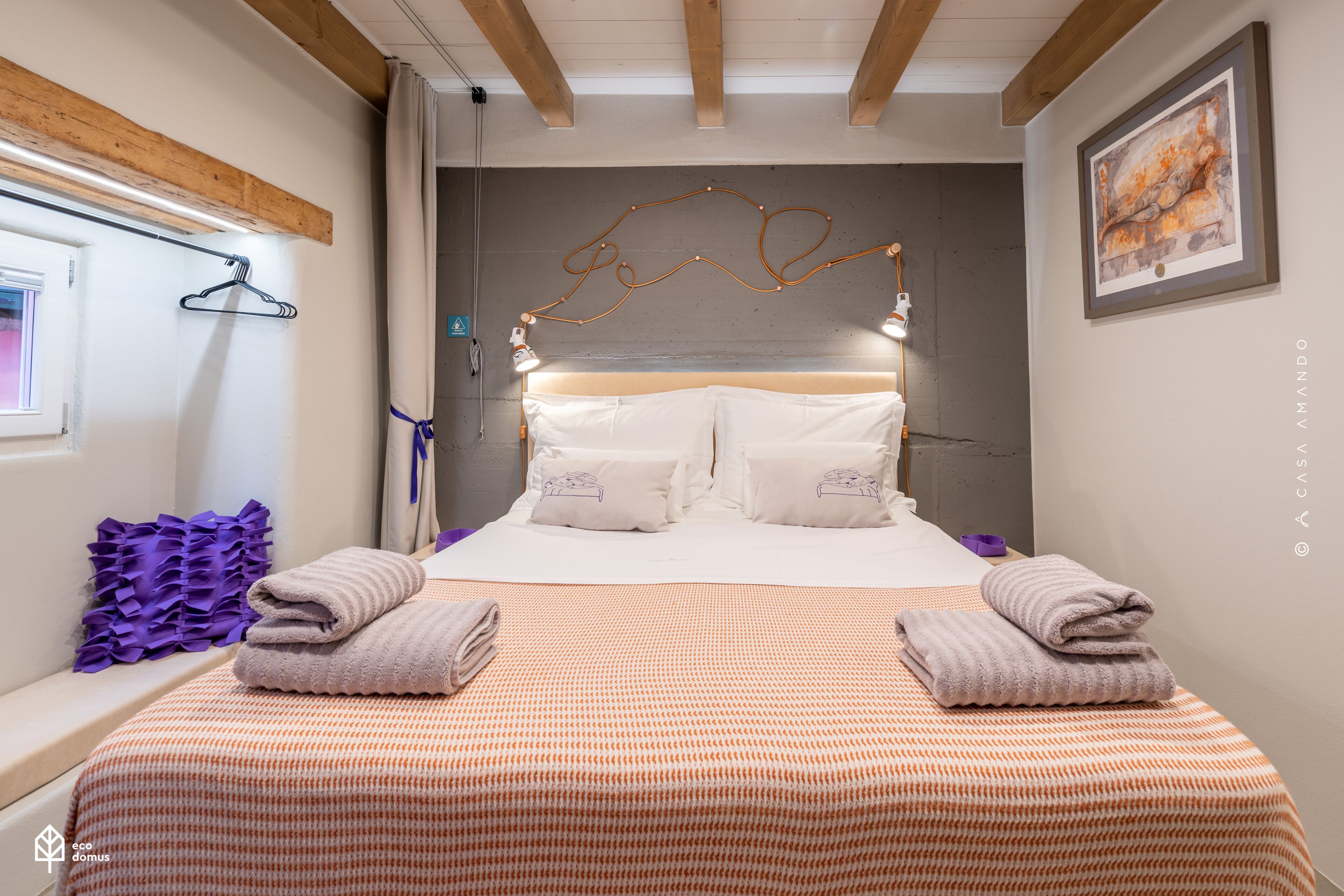 Un lit bien fait, avec une couvre-lit à motifs, deux oreillers et des serviettes pliées.