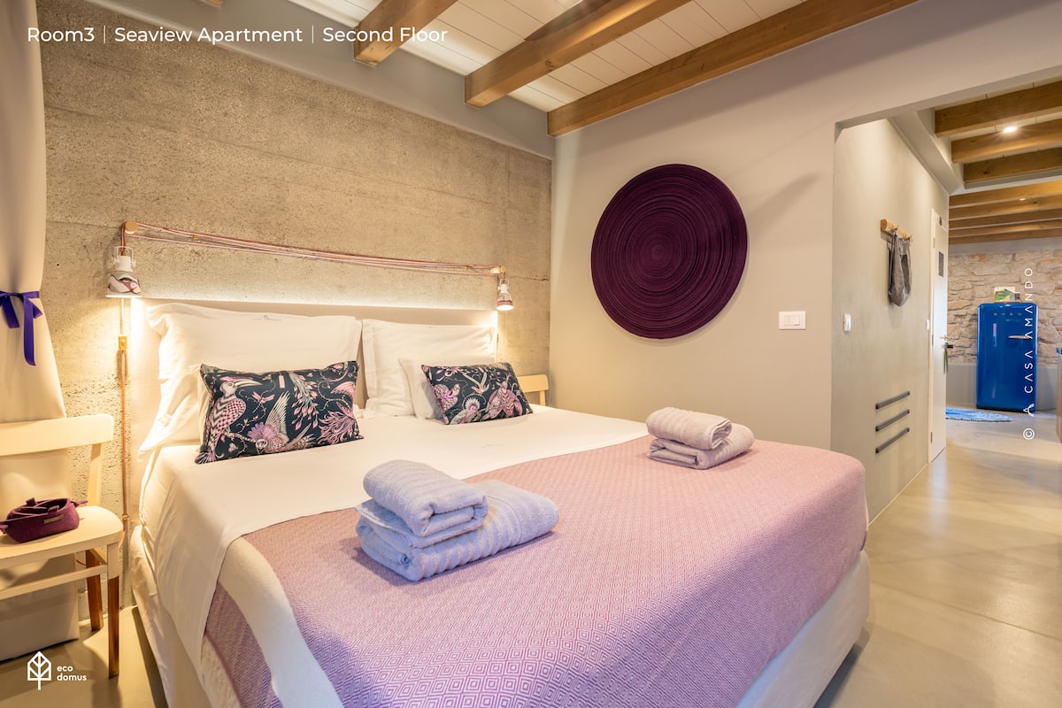 A bedroom with a large bed, a headboard, a wall-mounted circular decoration, and a wooden ceiling.