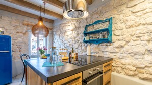 A kitchen with a stone wall, wooden cabinets, and a blue refrigerator. - Casa Amando Eco Boutique House (Rovinj)