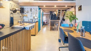 A modern kitchen with a wooden countertop, hanging pots, and a dining area with a blue chair and a table. - Casa Amando Eco Boutique House (Rovinj)