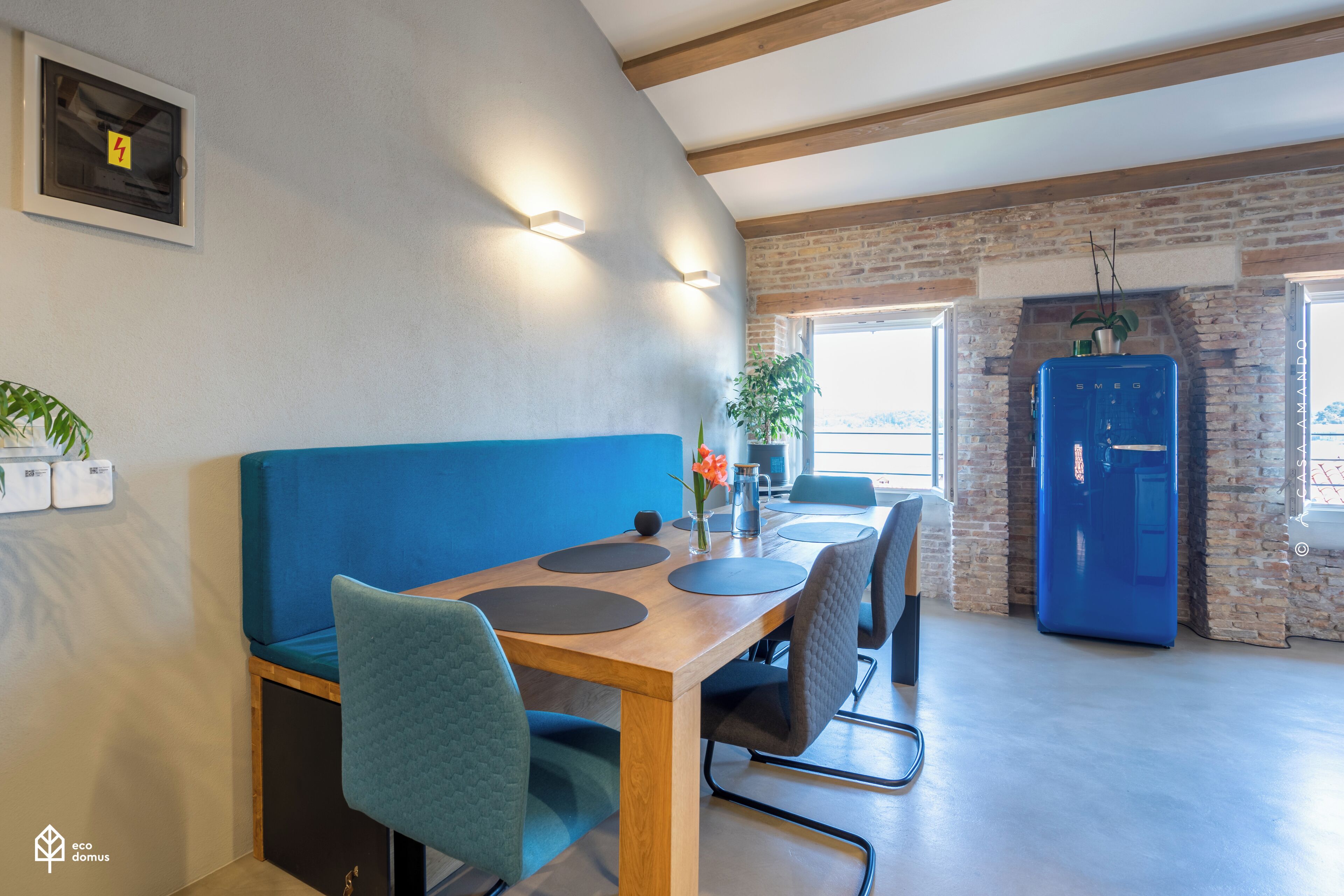 A dining area with a wooden table, blue cushioned bench, and modern chairs.