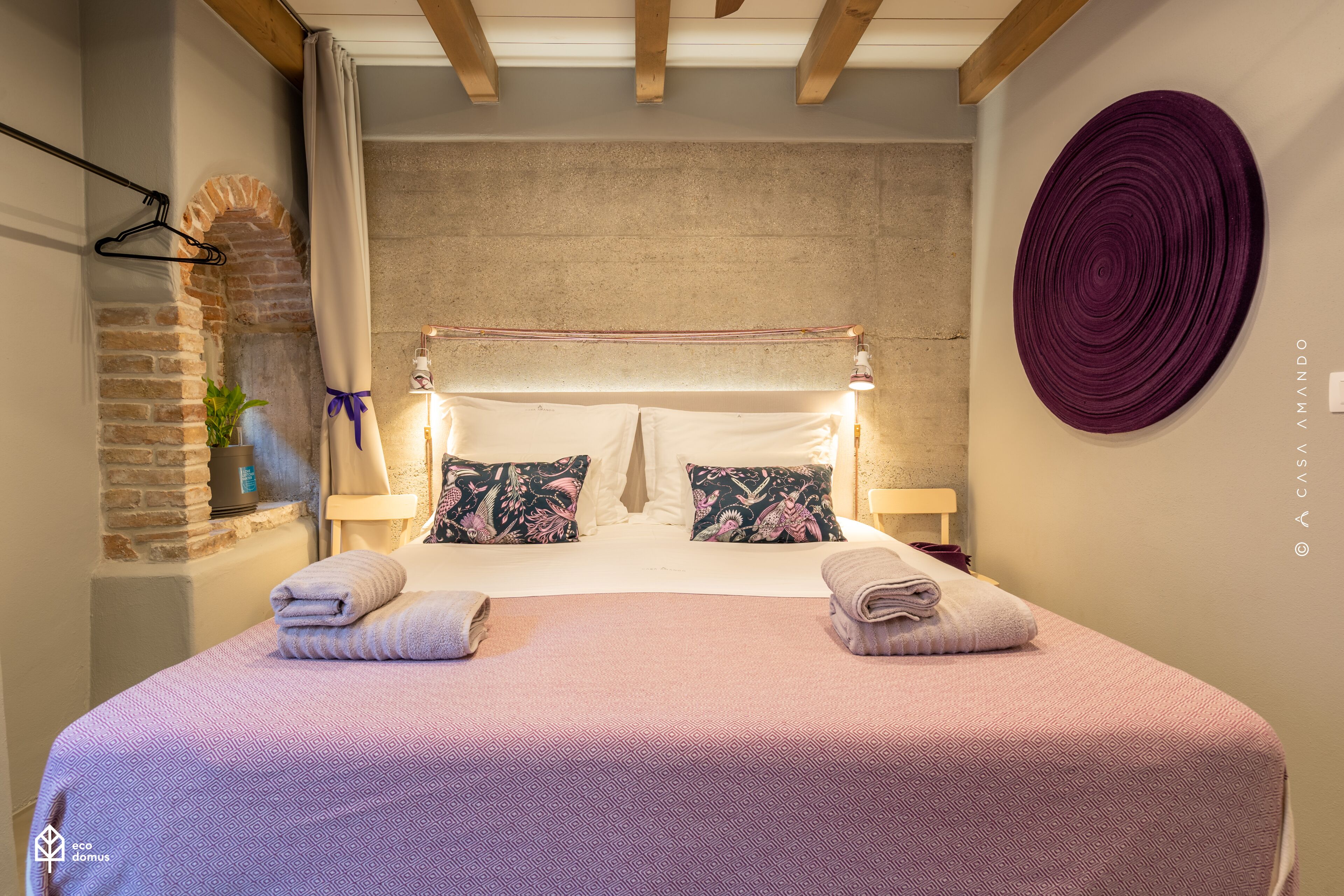 A bedroom with a bed, pillows, and a wall-mounted circular decoration.