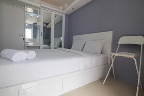 Ein Schlafzimmer mit einem Bett, einem weißen Stuhl, einem Kleiderschrank und einem Spiegel.